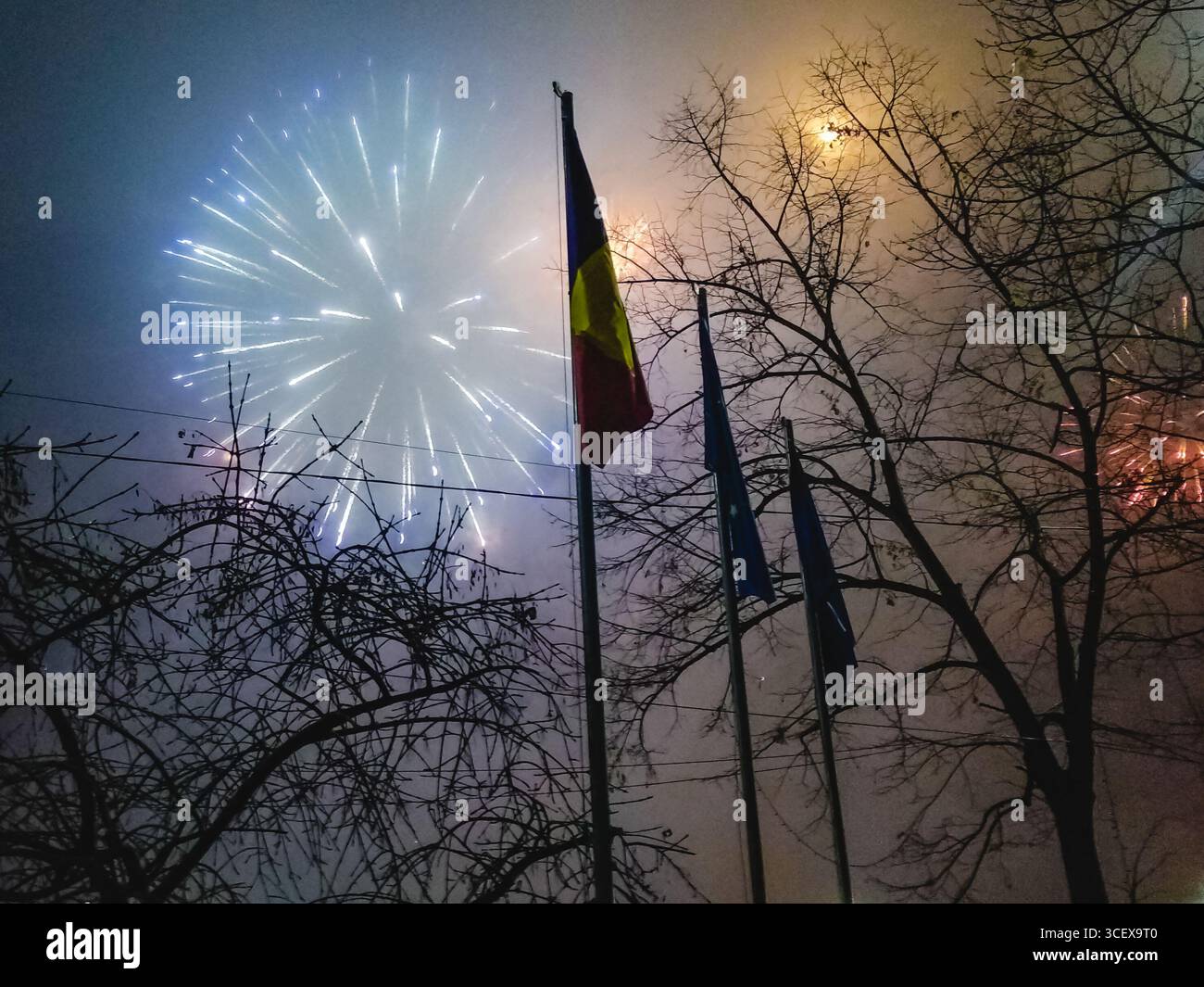 Drapeau roumain et feux d'artifice illuminant le ciel pendant les célébrations du nouvel an à Bucarest, Roumanie. Une scène festive du 31 décembre 2019. Banque D'Images