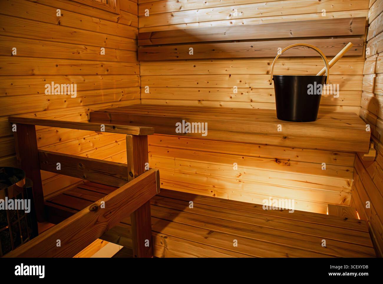 Petit sauna finlandais pour deux personnes à l'intérieur. Seau de sauna de couleur noire et louche de sauna sur banc de bois. Banque D'Images