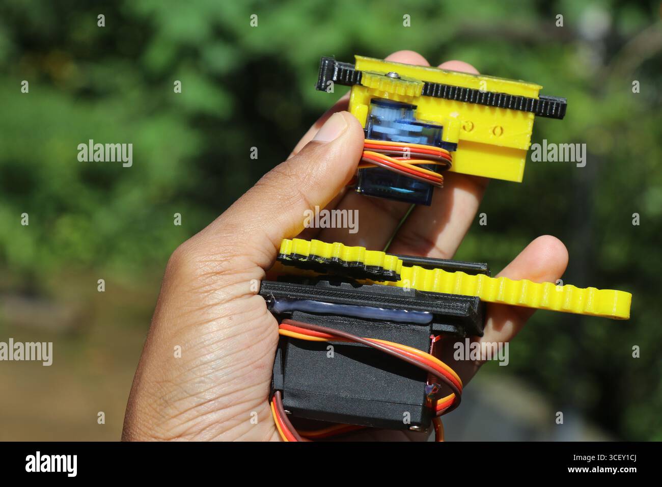 Servomoteur de petite et moyenne taille avec son arbre relié à des mécanismes de curseur imprimés en 3d tenus dans la main. Servomoteurs pour projets robotiques Banque D'Images