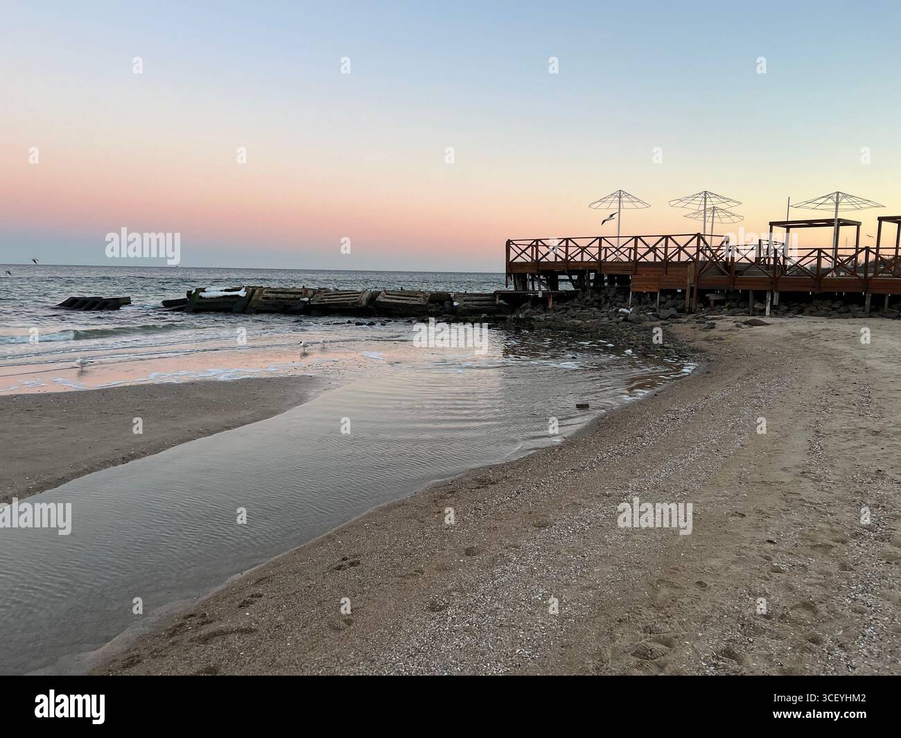 Un doux coucher de soleil rose sur la plage de la mer Noire, s'étendant du ciel rose au ciel bleu Banque D'Images