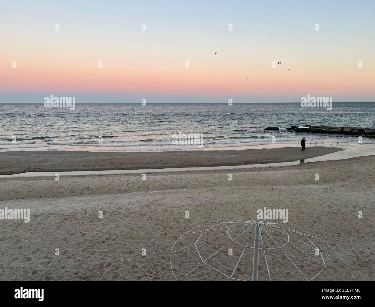 Un doux coucher de soleil rose sur la plage de la mer Noire, s'étendant du ciel rose au ciel bleu Banque D'Images