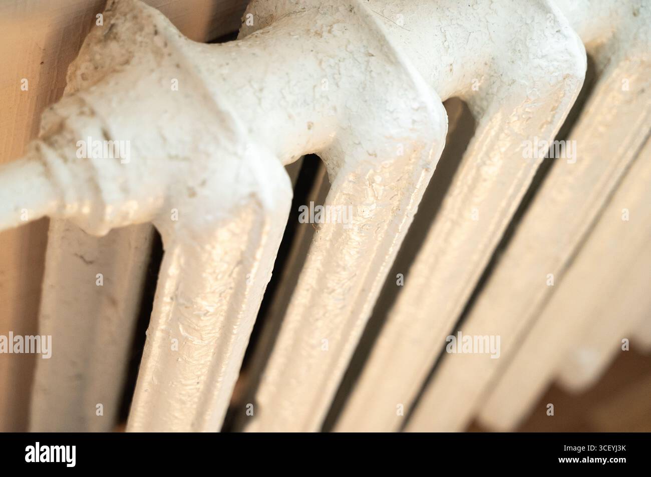 Un gros plan détaillé d'un vieux radiateur blanc, mettant en valeur son charme vintage et des textures qui racontent une histoire Banque D'Images