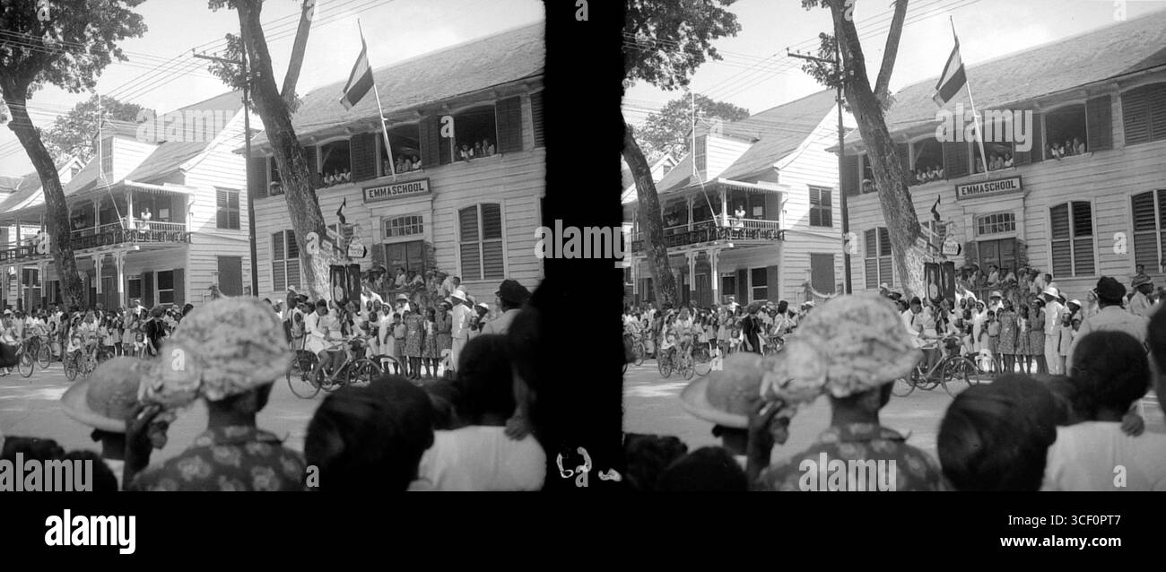 Les enfants à vélo passent avec des portraits de la princesse Juliana et du prince Bernhard peu après la naissance de la princesse Marijke en 1947. Cette image stéréoscopique reflète la joie nationale et l'importance de la famille royale à cette époque. Banque D'Images