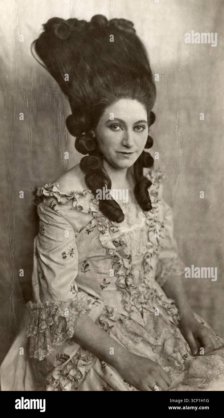 Une femme dans une robe historique avec de longs cheveux coiffés dans une coiffure Louis XVI, avec des cheveux debout et tombant en balles de chaque côté, pays-Bas, 1922. Banque D'Images