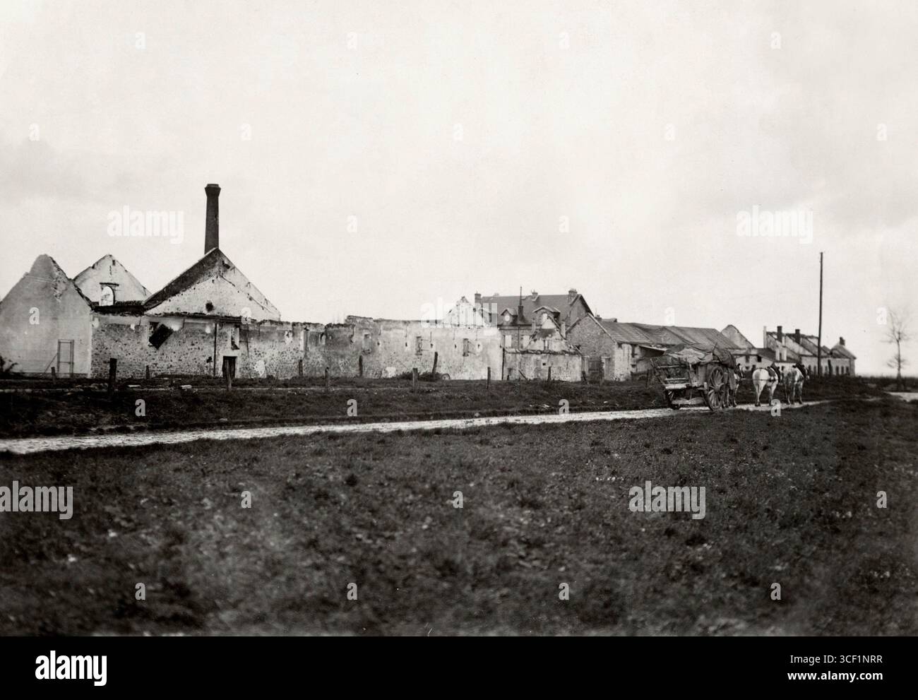 Ruines d'une ferme à Reez-fosse-Martin, en Picardie, pendant la première Guerre mondiale. Des murs, une cheminée et des toits endommagés subsistent. Un chariot tiré par deux chevaux est vu sur la route. Reez-fosse-Martin, 1914. Banque D'Images