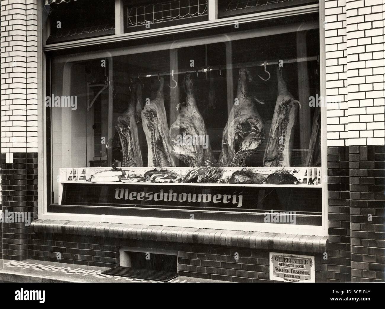 La vitrine de la boucherie de Hendrik Pasman à Steenwijk, 1929 ans, montre des carcasses de viande suspendues. Cette présentation met en évidence les offres de la boutique, une pratique courante dans les boucheries traditionnelles de l'époque aux pays-Bas. Banque D'Images