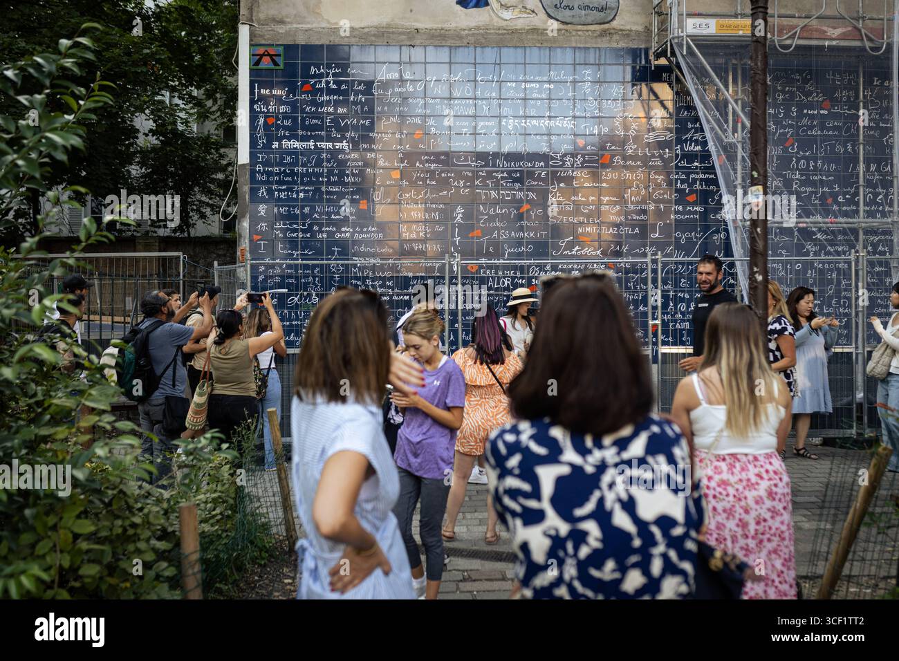 Les touristes prennent des photos devant le mur des je t'aime dans le quartier de Montmartre. La vie quotidienne dans le quartier de Montmartre, dans le 18ème arrondissement de Paris, célèbre pour sa Basilique du Sacré-cœur au sommet de la colline avec une magnifique vue panoramique sur Paris, ce qui en fait l’un des quartiers les plus touristiques de la ville. Banque D'Images