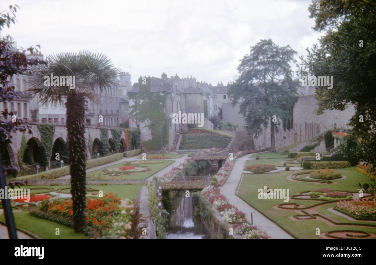 Jardins des remparts formels à vannes, France, avec parterres de fleurs bien entretenus, ruisseau, ponts, et murailles médiévales. Août 1963, film de diapositive 35mm. Banque D'Images