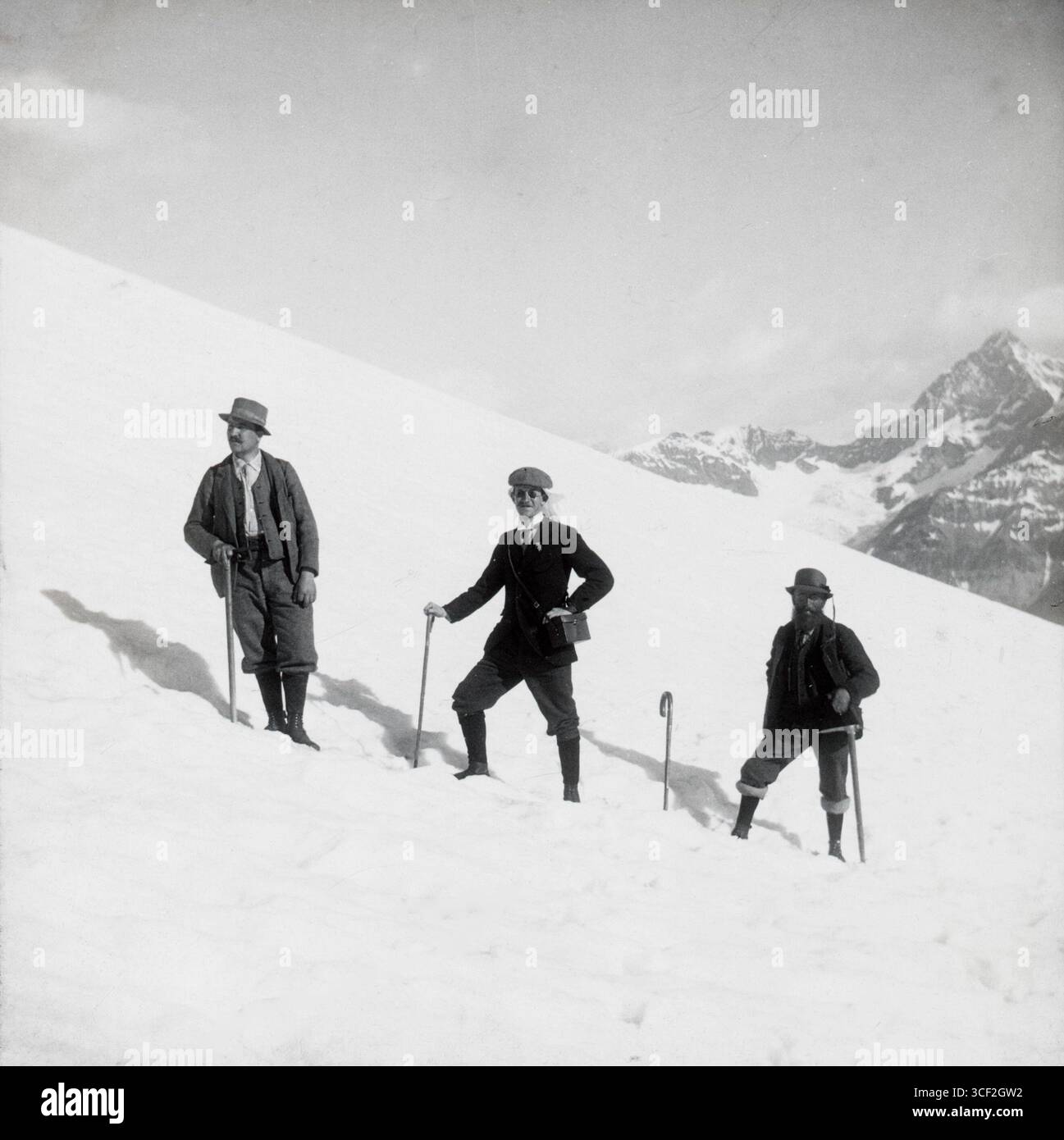 Trois hommes posent pour une photographie sur des montagnes enneigées près de Zermatt, en Suisse, vers 1900-1930, mettant en valeur le sport d'hiver populaire de l'alpinisme. Banque D'Images
