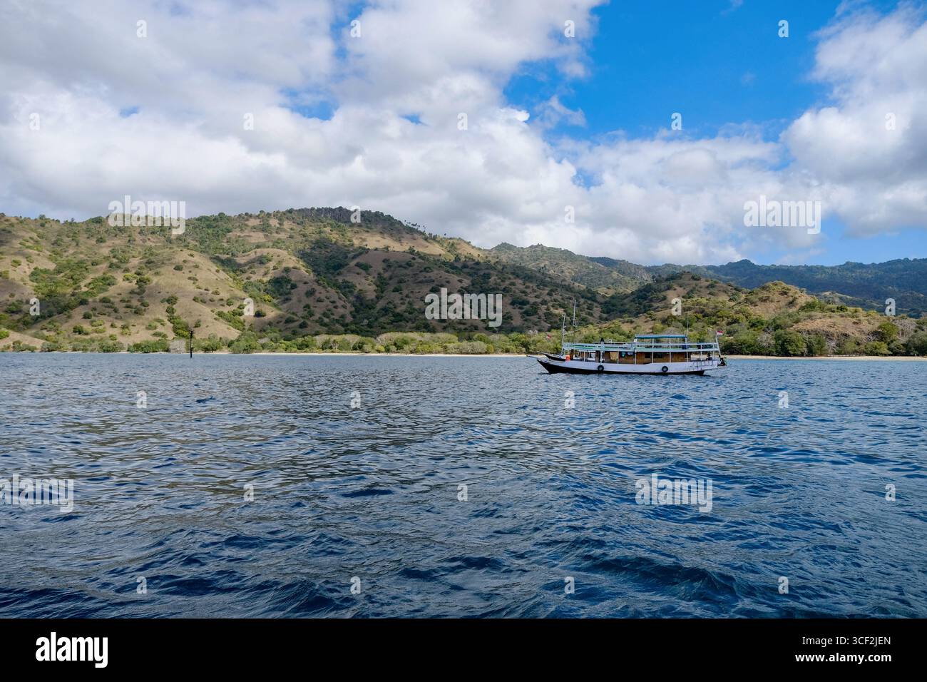 Naviguer à travers la sérénité, où les eaux bleues rencontrent les collines verdoyantes sous le ciel ouvert. Banque D'Images