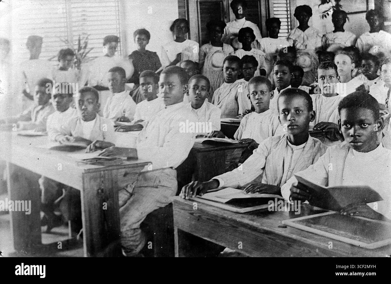 Ce négatif en verre de 1900-1930 montre les élèves dans une salle de classe. La photographie met en lumière le milieu éducatif et le processus d’apprentissage au début du XXe siècle. Banque D'Images