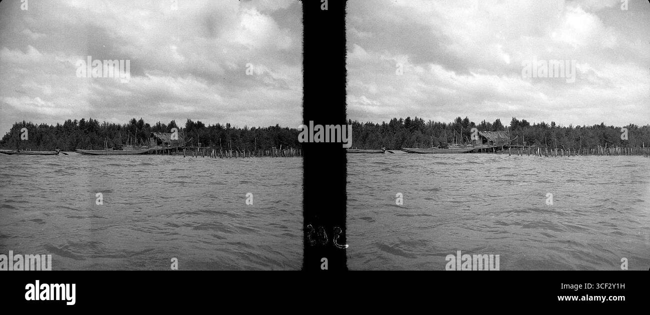 Cette photographie stéréoscopique de 1946-1947 montre un camp de pêche situé à l'embouchure de la rivière Saramacca au Suriname. L'image donne un aperçu de la vie quotidienne des gens qui vivent dans cette communauté riveraine. La taille de la photographie est de 6 x 13 cm (2 3/8 x 5 1/8 po). Banque D'Images