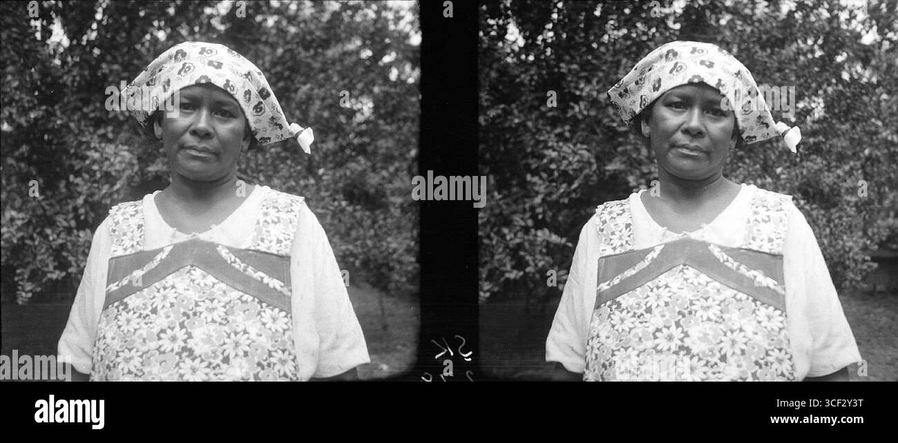 Cette photographie stéréoscopique de 1940 représente Lena, une femme de chambre créole travaillant pour le professeur Stahel au Suriname. L'image la capture dans un environnement personnel et domestique, offrant un aperçu de la dynamique sociale de l'époque. La photographie mesure 6 x 12,7 cm (2 3/8 x 5 po). Banque D'Images