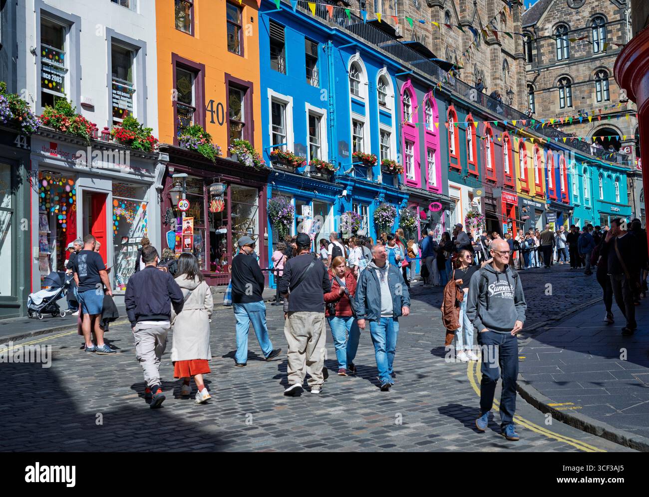Édimbourg, Écosse, Royaume-Uni. 20 août 2025. Vues sur la vieille ville d'Édimbourg pendant Fringe et Festival International avec bars et restaurants en plein air très occupés sous un soleil chaud. Pic ; touristes sur la célèbre rue Victoria avec des vitrines colorées. Iain Masterton/Alamy Live News. Banque D'Images