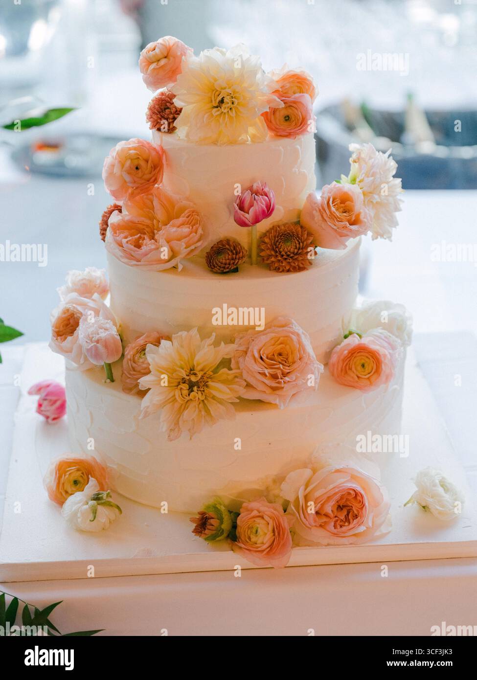 Un superbe gâteau de mariage orné de fleurs vibrantes, élégamment présenté lors d'une joyeuse célébration. Banque D'Images