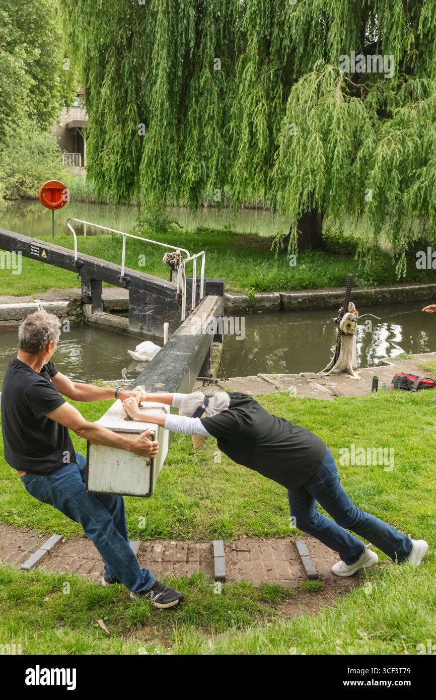 Angleterre, Somerset, Bath, le canal Kennet et Avon, Widcombe Lock et Thimble Mill Lock, couple ouvrant les portes de l'écluse Banque D'Images