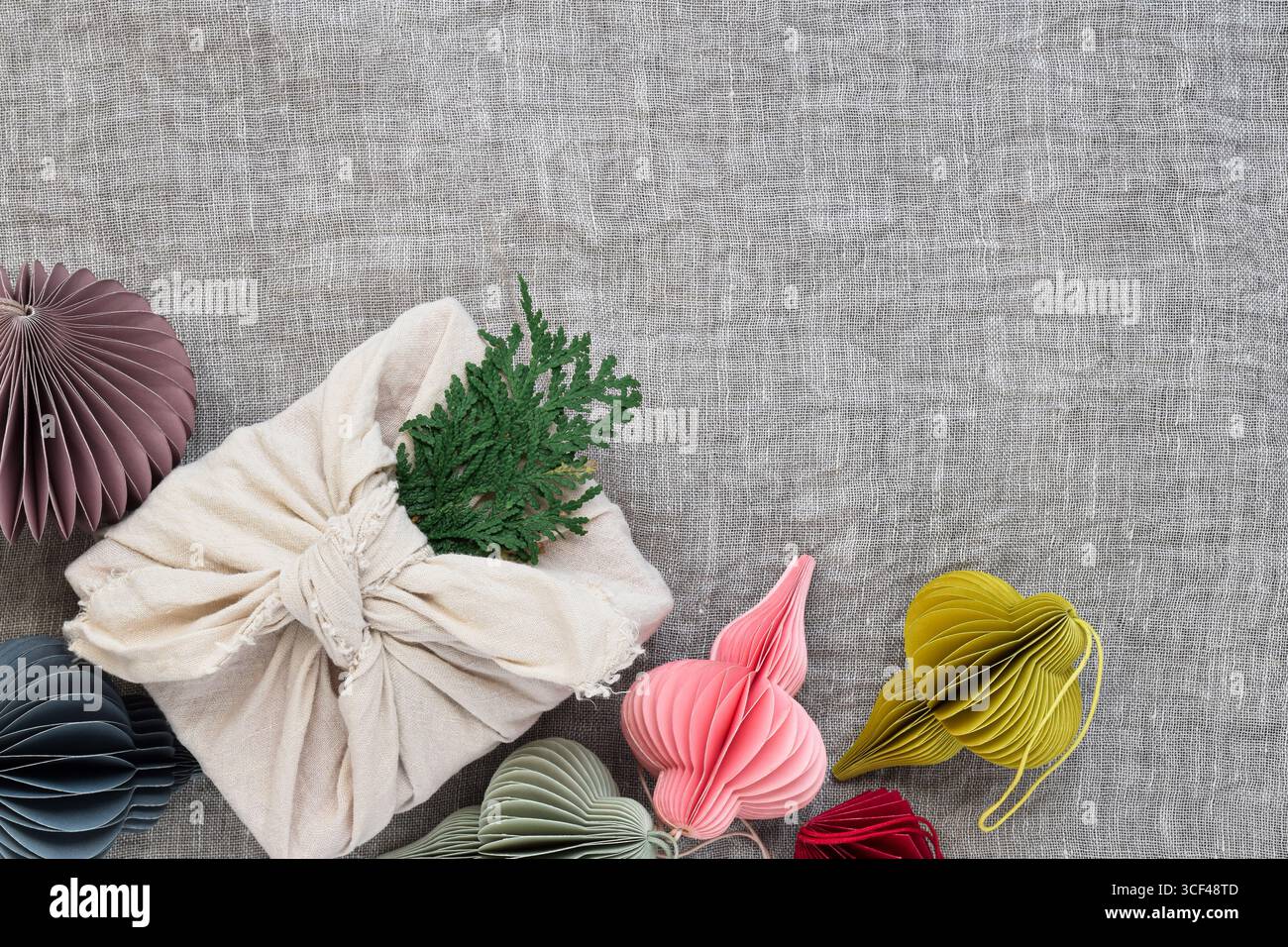 Cadeau de noël enveloppé de lin avec ornements en papier multicolore en nid d'abeille faits à la main, emballage cadeau écologique réutilisable, vue de haut en bas flatlay avec copie Banque D'Images
