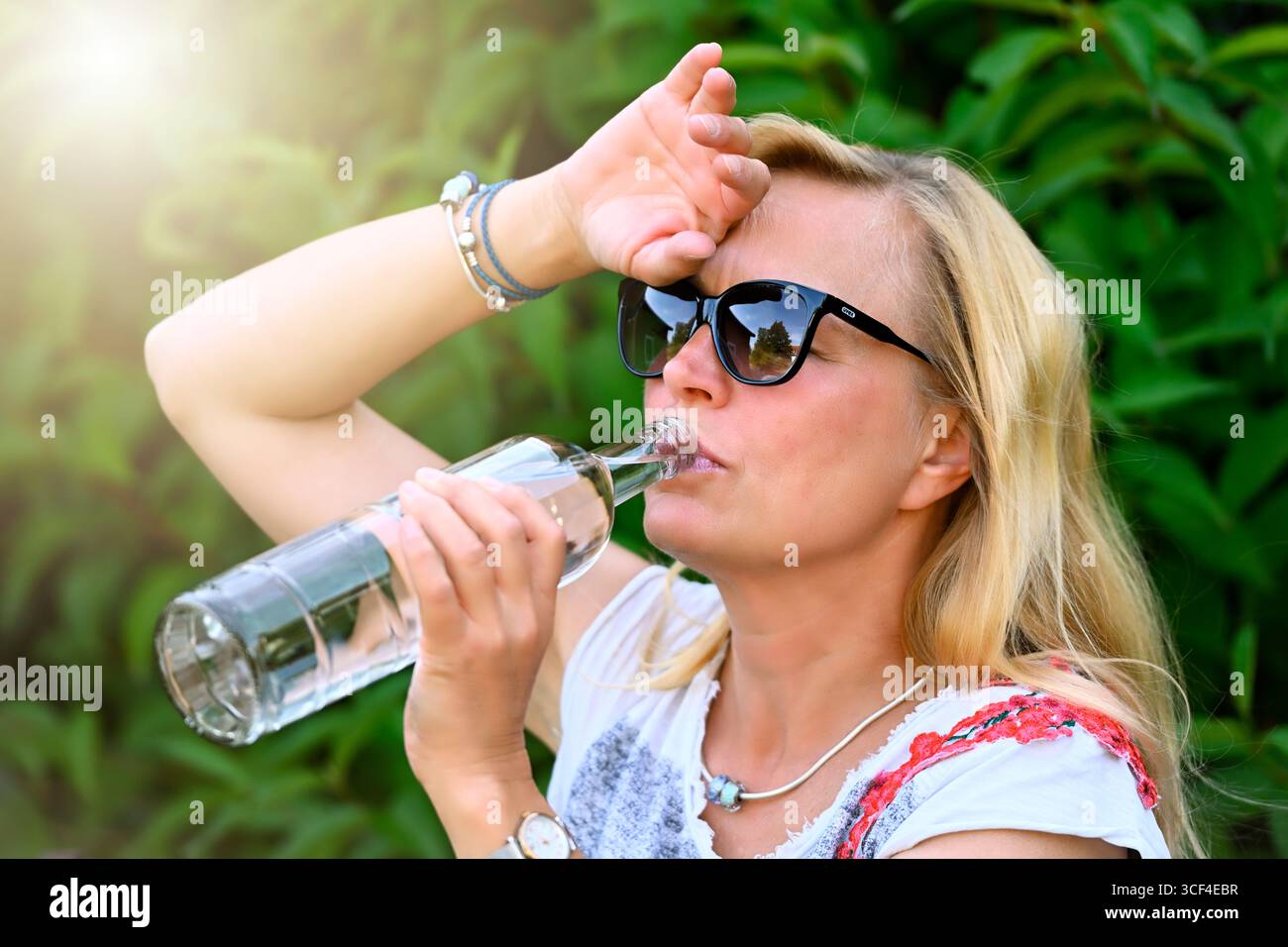 Femme buvant de l'eau dans la chaleur estivale, vague de chaleur photo symbolique Banque D'Images