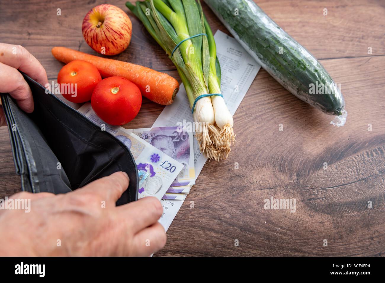 Un coût de la vie au Royaume-Uni, concept d'inflation avec une personne tenant un sac à main vide sur une table avec des billets de banque en livres sterling, un reçu d'épicerie et quelques légumes. Banque D'Images
