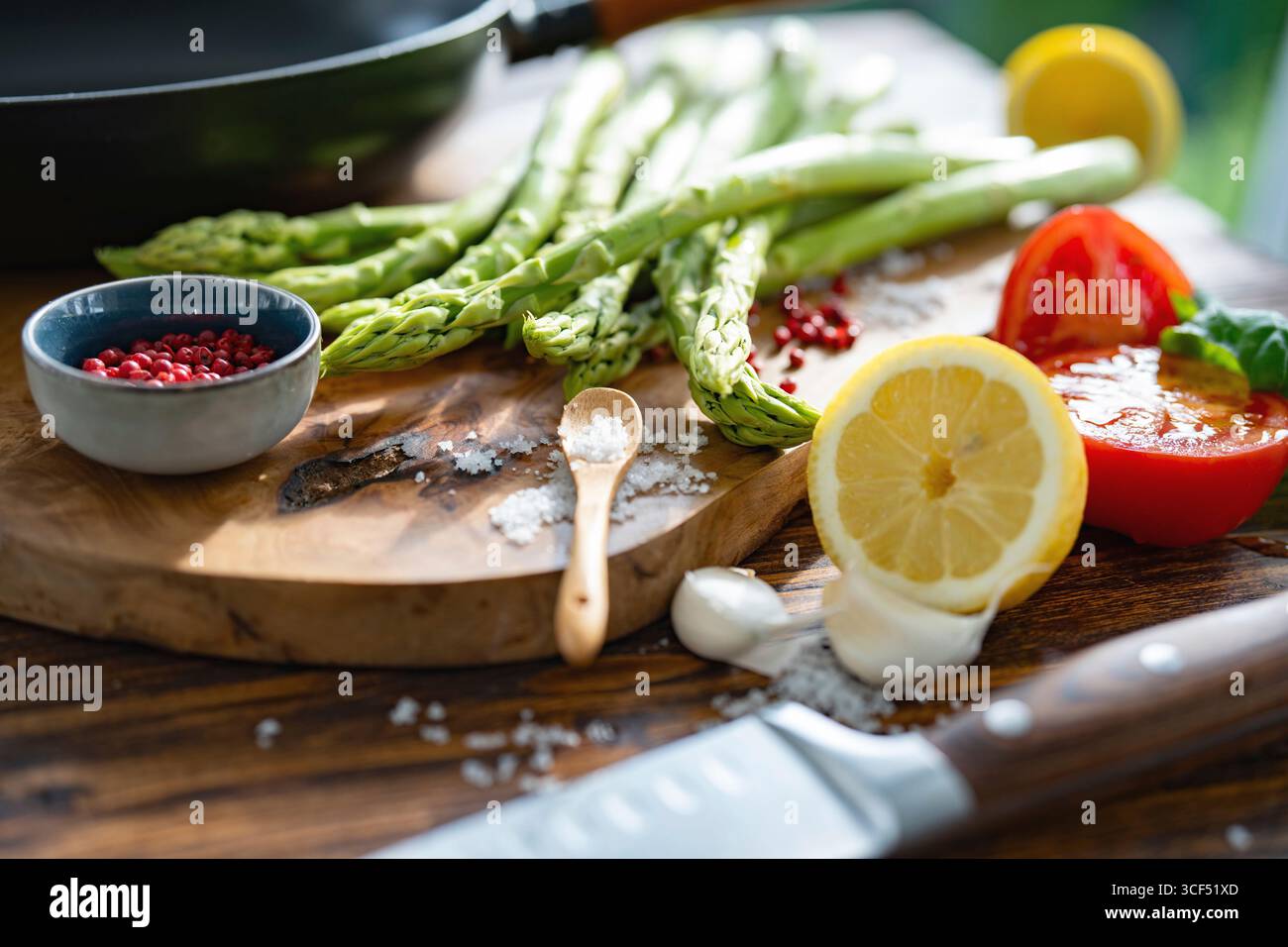 Ingrédients frais pour asperges vertes rôties. Légumes locaux et une poêle en fonte sur une table en bois rustique. Gros plan avec faible profondeur de champ. Banque D'Images