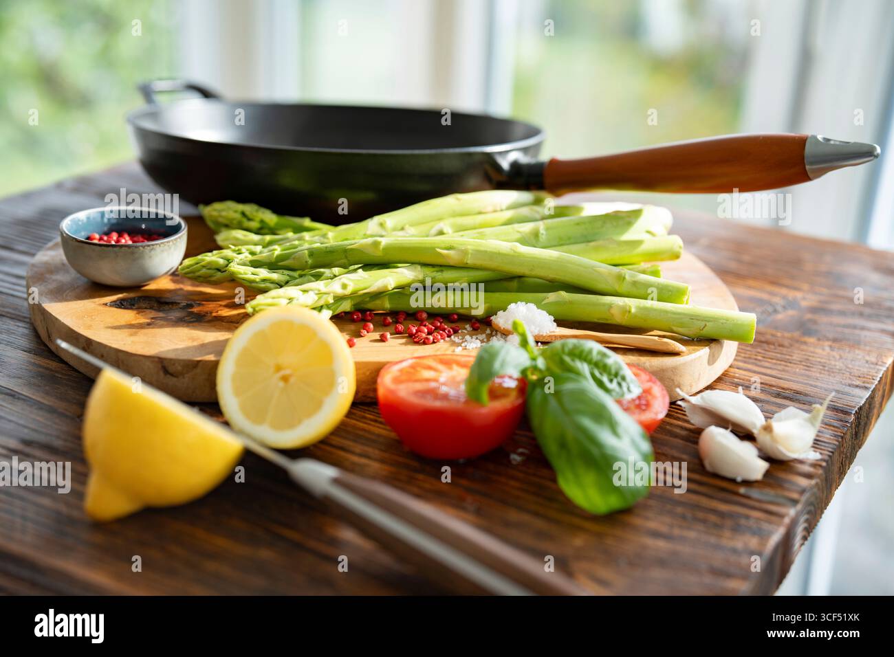 Ingrédients pour rôtir les asperges vertes. Légumes locaux et une poêle en fonte avec poignée en bois sur bois rustique. Préparation de légumes frais pour une alimentation saine. Banque D'Images