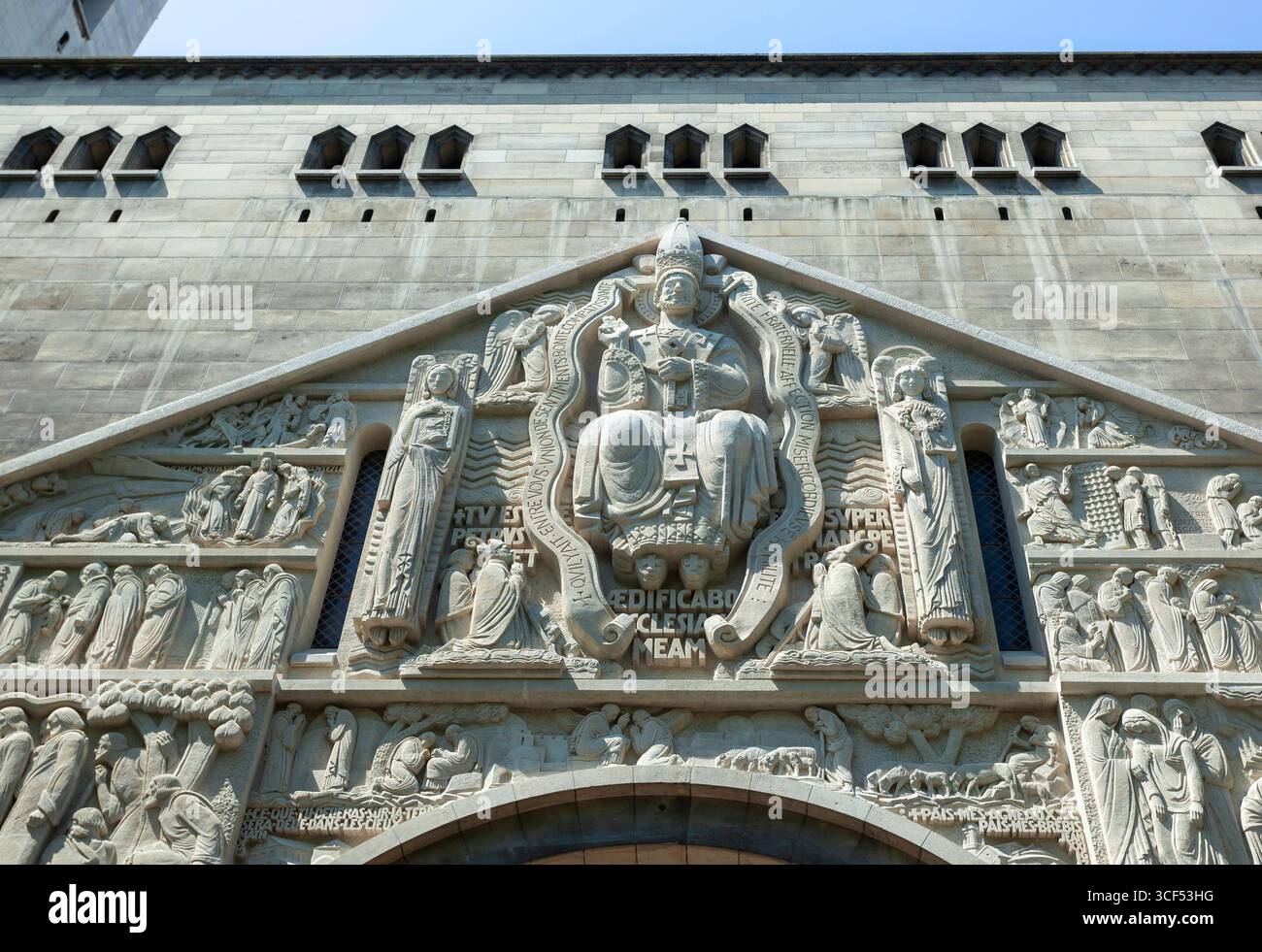 Sculpture en pierre complexe au-dessus de l'entrée d'une église représentant une scène religieuse avec une figure centrale entourée d'anges et d'autres figures bibliques Banque D'Images
