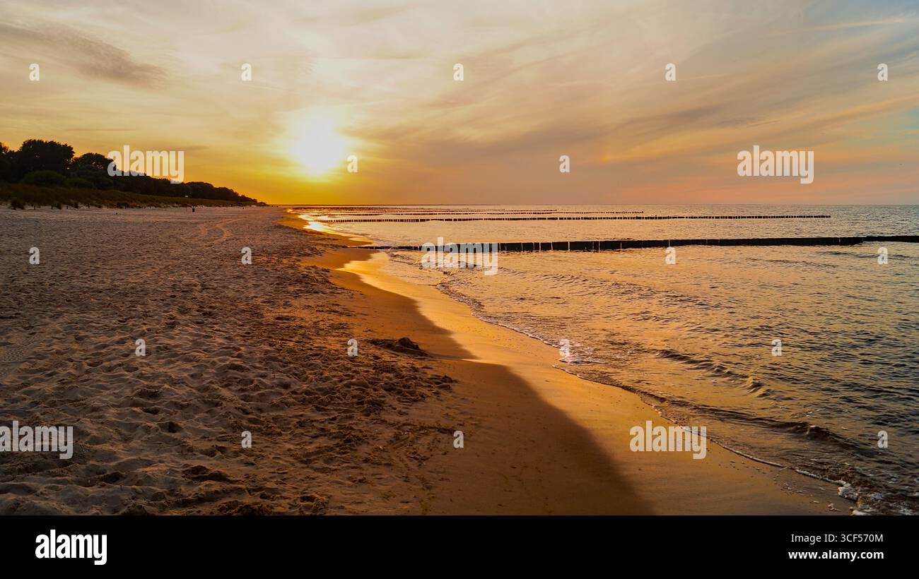 Coucher de soleil sur la plage de Zinnowitz sur l'île d'Usedom avec le ciel rouge vif du soir - spectaculaire paysage côtier de la mer Baltique. Banque D'Images