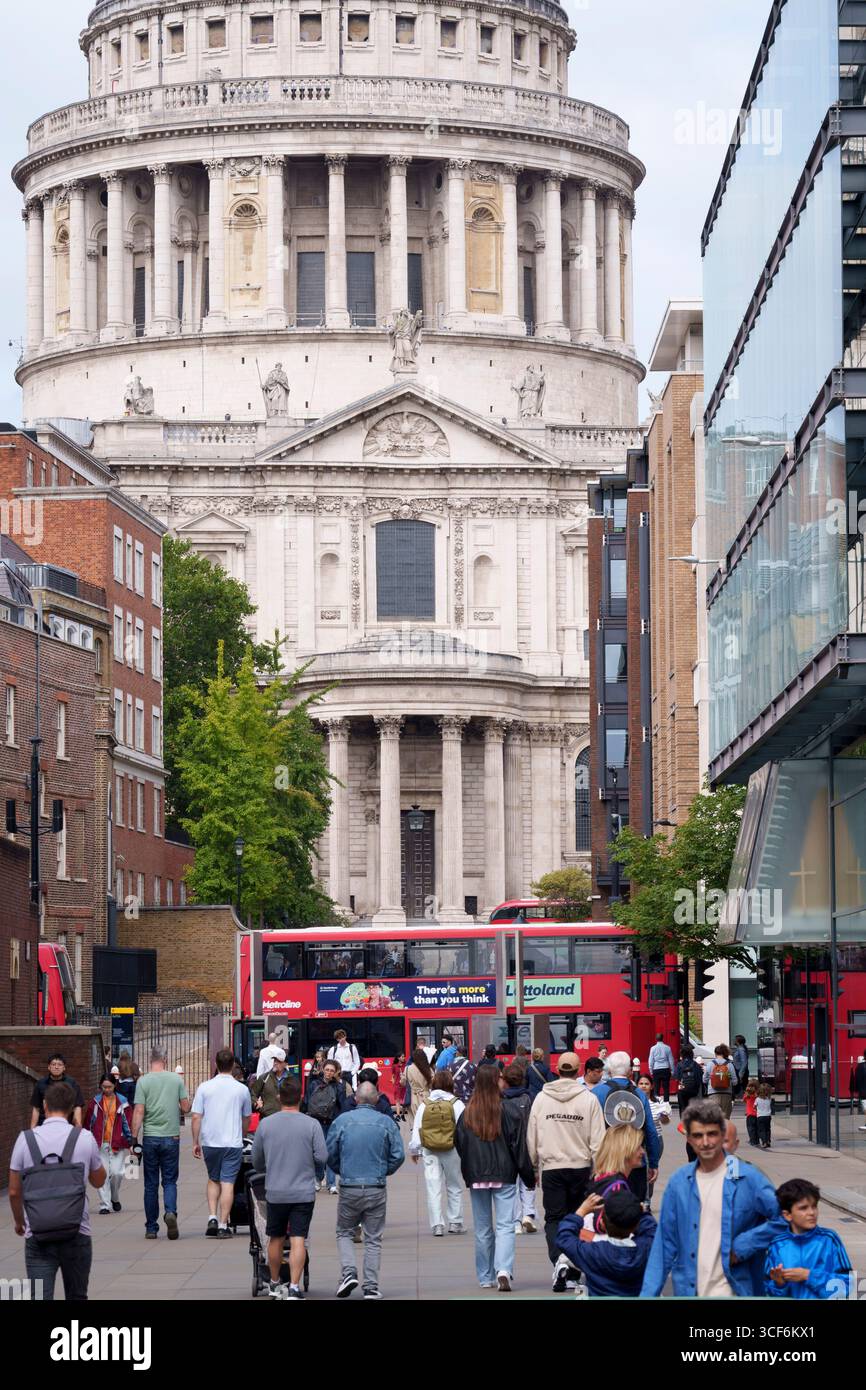 Sous l'architecture en dôme de la cathédrale Saint-Paul, les piétons marchent le long de Peter's Hill dans la Cité de Londres, le quartier financier de la capitale, le 20 août 2025, à Londres, en Angleterre. Banque D'Images