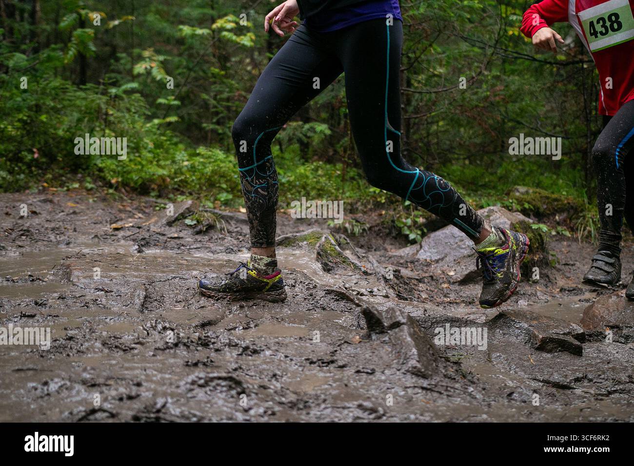 Jambes femme athlète courir de la boue et des rochers pendant la course de marathon Banque D'Images