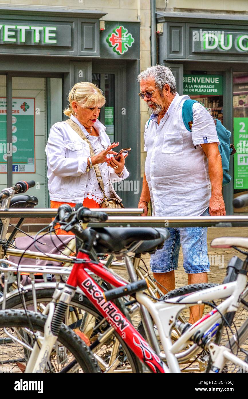Homme mature et femme / touristes regardant un smartphone pour des informations ou des directions dans le vieux quartier de Tours, Indre-et-Loire (37), France. Banque D'Images