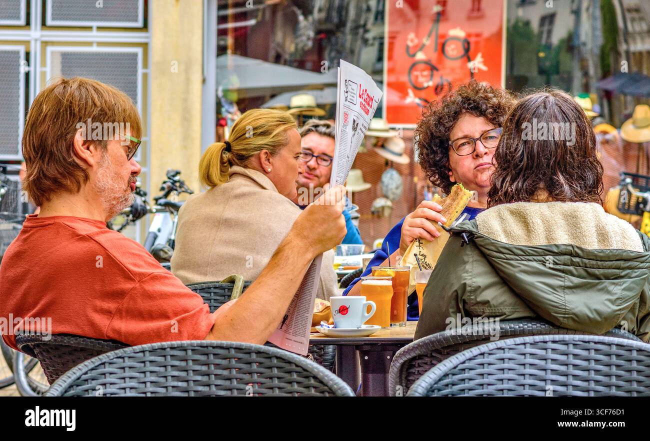 Hommes et femmes parlant, lisant et socialisant à des tables de café en plein air dans le vieux quartier de Tours, Indre-et-Loire (37), France. Banque D'Images