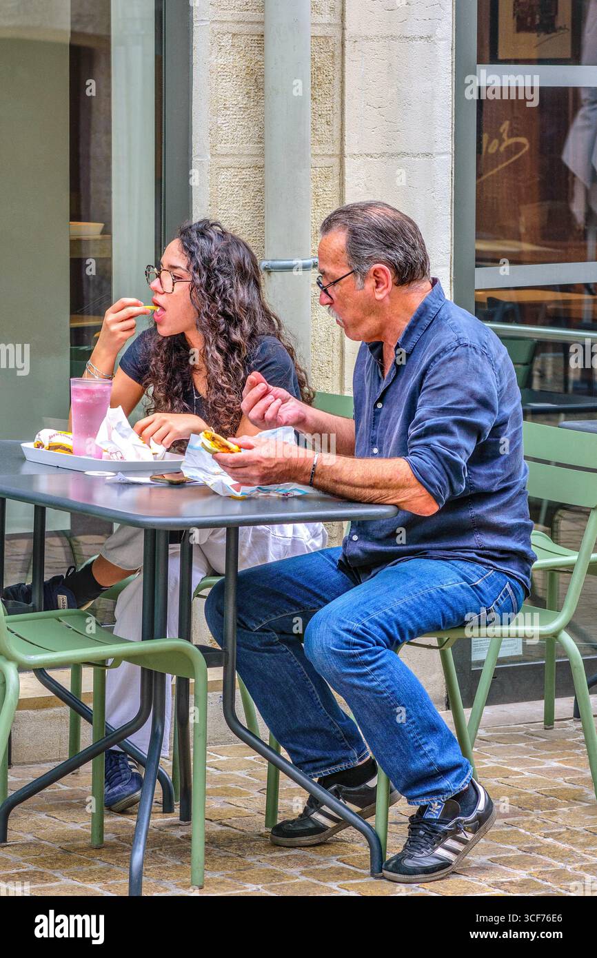 Couple assis à table de café / bistro / restaurant en plein air pour déjeuner dans le vieux quartier de Tours, Indre-et-Loire (37), France. Banque D'Images