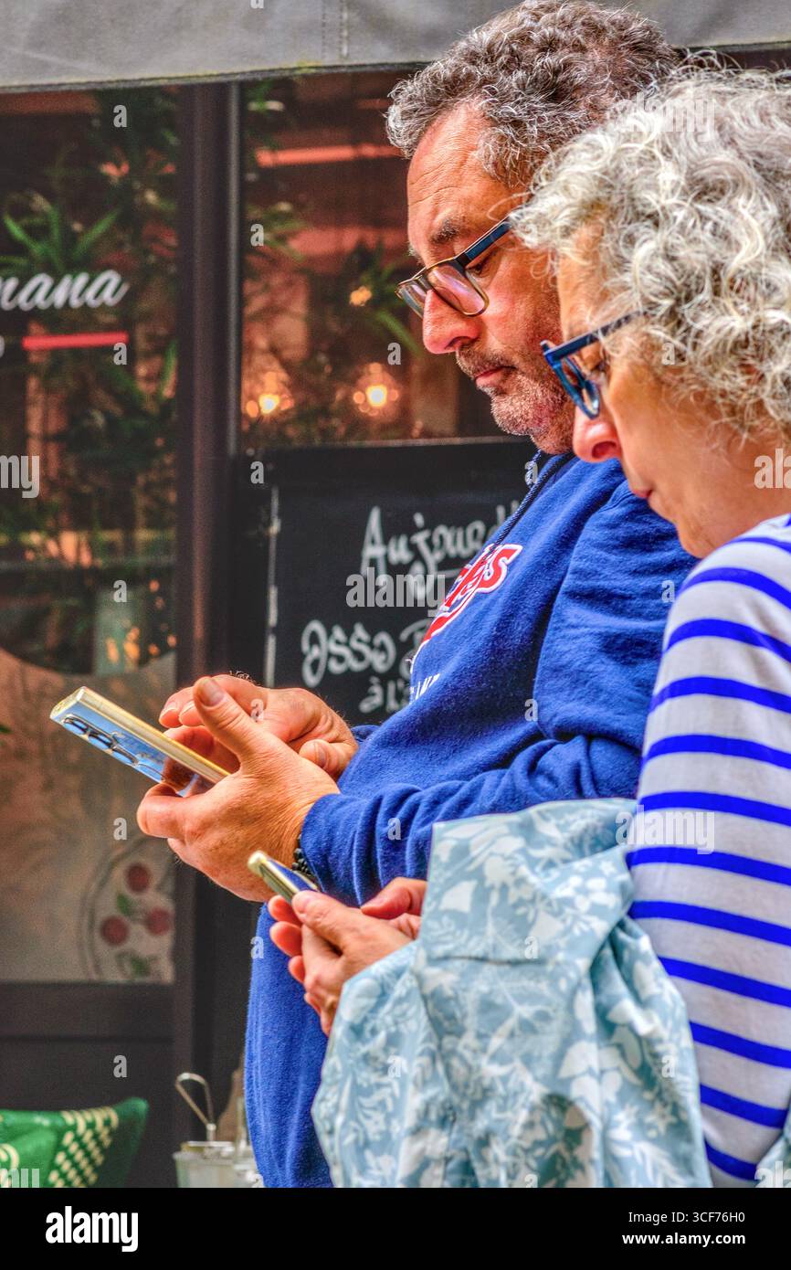 Couple mature regardant leurs smartphones (pour les directions ?) Dans le vieux quartier de Tours, Indre-et-Loire (37), France. Banque D'Images