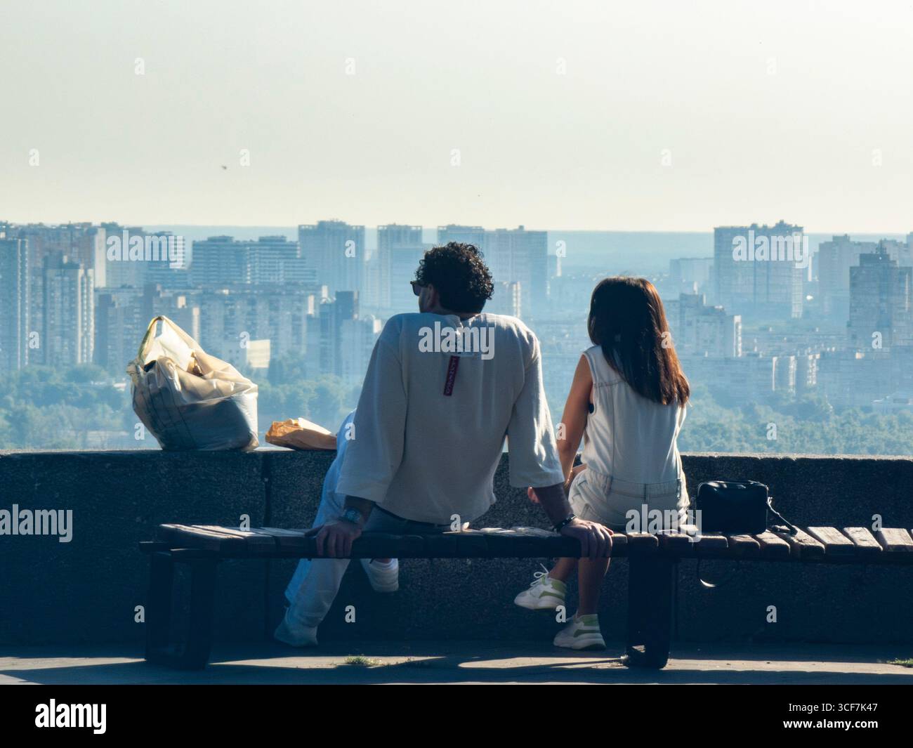 Kiev, Ukraine - 20 juillet 2025 : touristes assis sur un banc, profitant de l'horizon urbain depuis un point de vue élevé dans le Parc de la gloire éternelle, Kiev, par une journée ensoleillée Banque D'Images