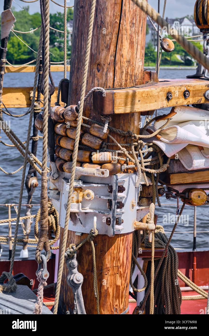 Mât de grand navire avec des yeux mortels en bois et des cordes de gréement soigneusement fixées, montrant l'artisanat nautique détaillé avec une partie d'une voile pliée, photographiée Banque D'Images