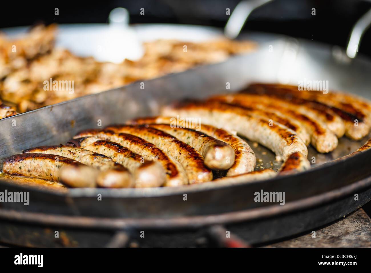 Saucisses frites traditionnelles étant cuit à la marché de printemps à Vilnius, Lituanie. Variété de délicieux aliments de rue sur la foire de Pâques. Banque D'Images