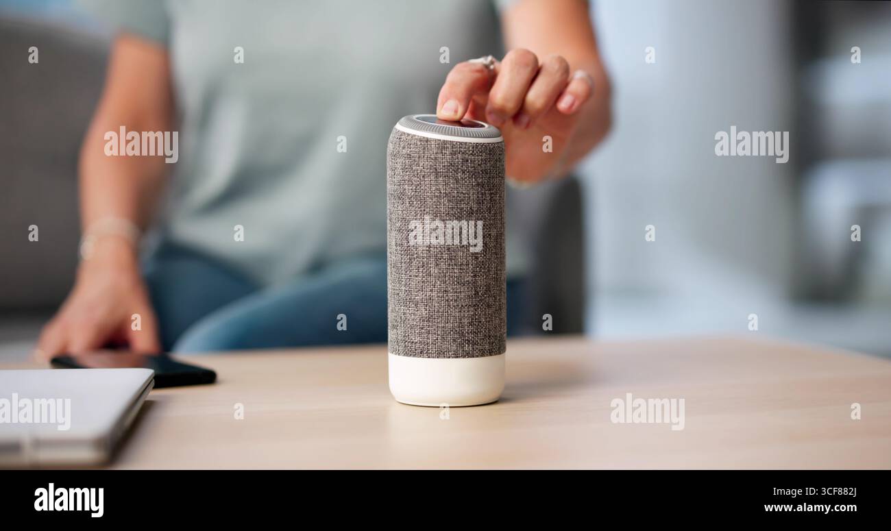 Femme senior ajustant haut-parleur intelligent sur la table blanche, écouter de la musique. Banque D'Images