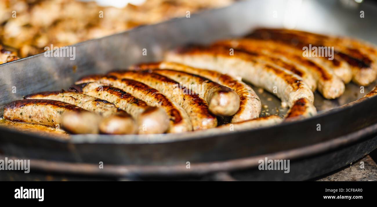 Saucisses frites traditionnelles étant cuit à la marché de printemps à Vilnius, Lituanie. Variété de délicieux aliments de rue sur la foire de Pâques. Banque D'Images