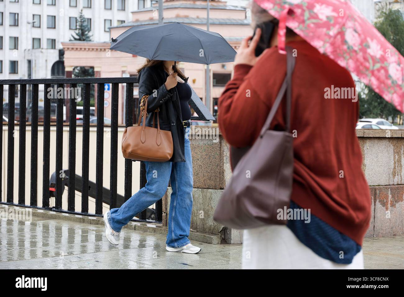 Femme avec parapluie marchant dans une rue. Les gens pendant la pluie en ville Banque D'Images