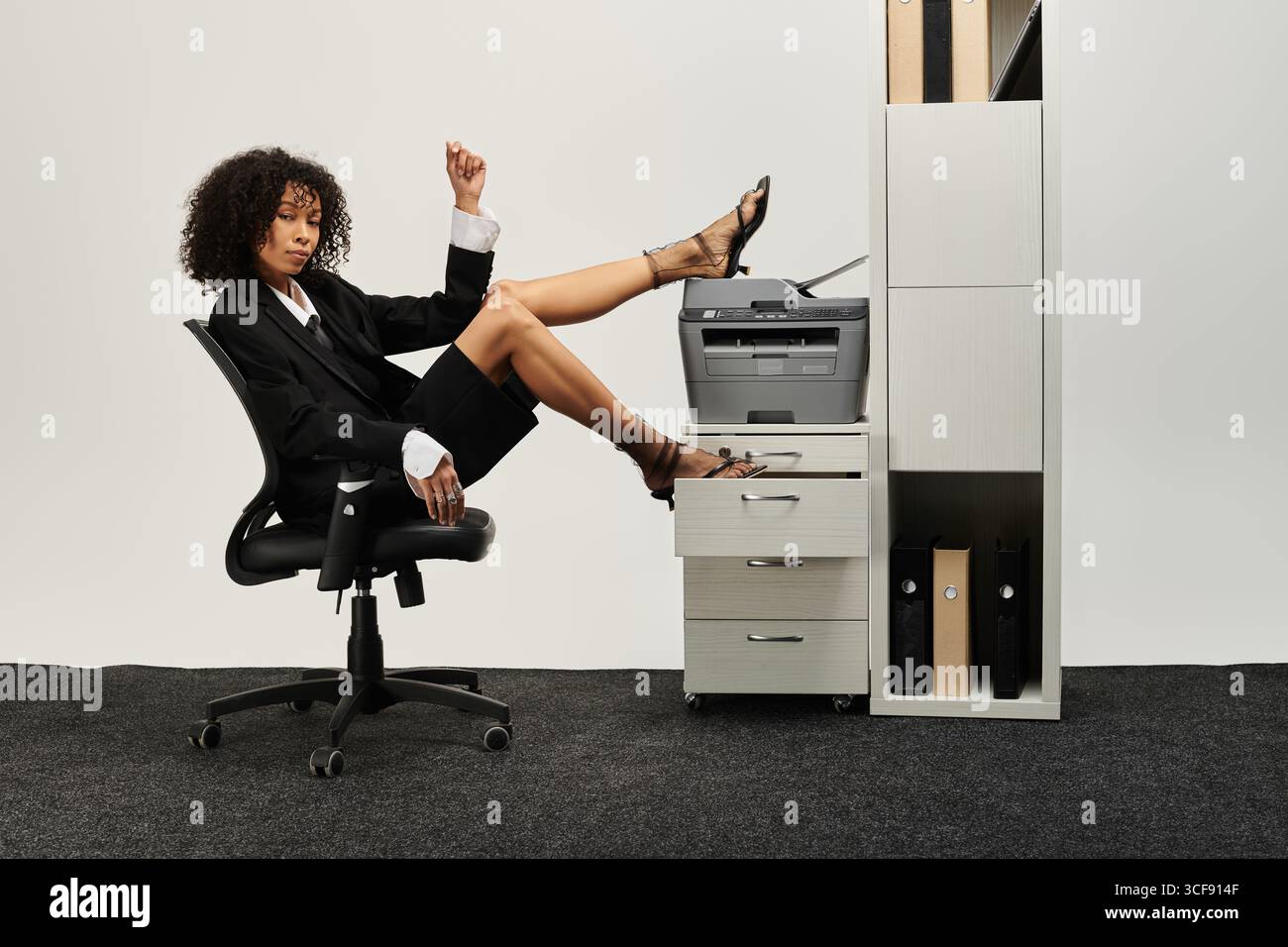 Une jeune femme pose en toute confiance dans une tenue d'affaires élégante dans un bureau minimaliste. Banque D'Images