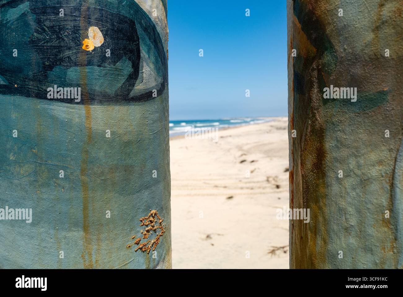 Oeil bleu sur les poteaux de bar en métal de clôture de mur peint regardant des plages de Playas de Tijuana au comté de San Diego. Banque D'Images