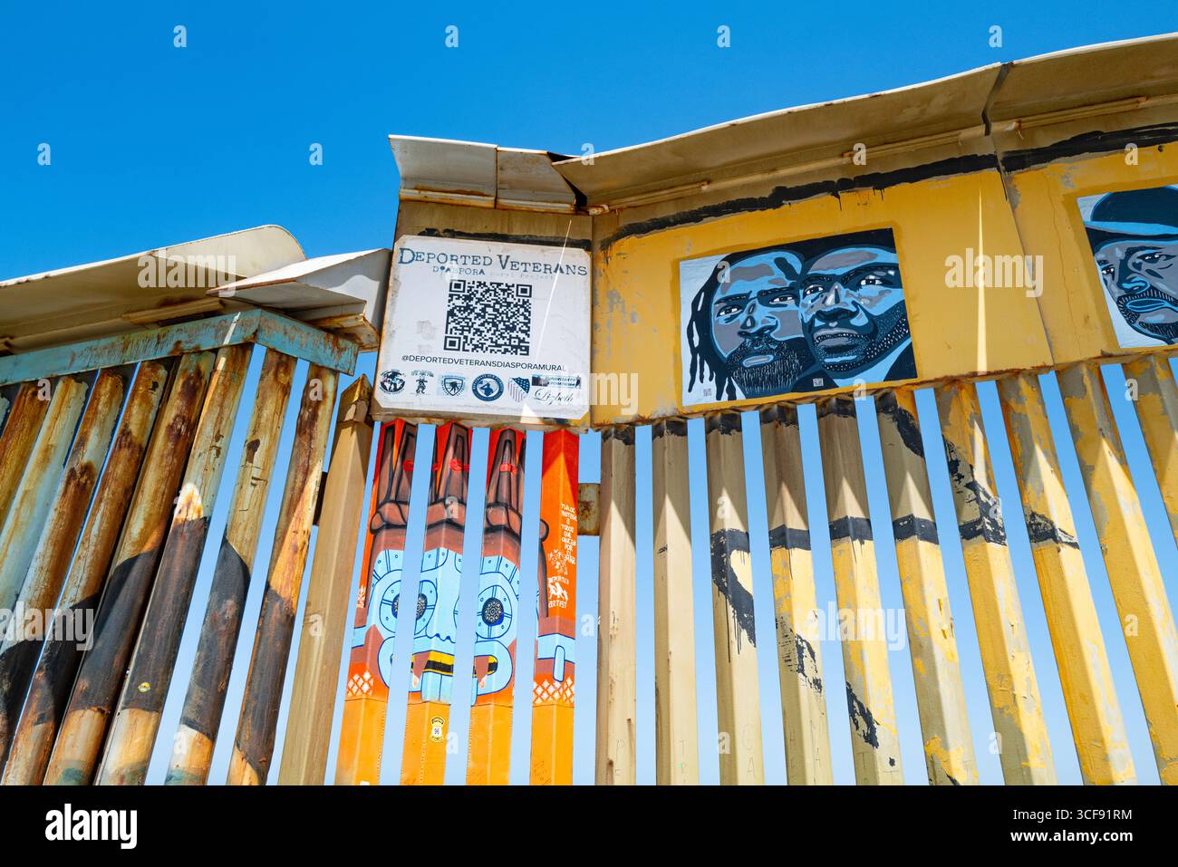 Un dépliant avec un code QR offrant de l'aide aux anciens combattants déportés est affiché sur une partie décorée du mur frontalier mexicain-californien. Banque D'Images