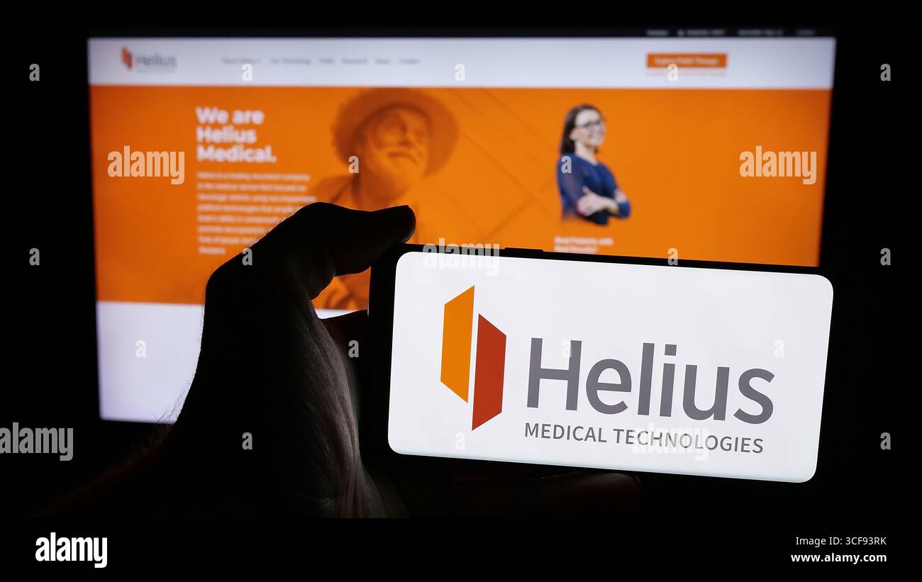 Stuttgart, Allemagne - 08-20-2025 : personne tenant un téléphone portable avec le logo de la société américaine Helius Medical technologies Inc. sur l'écran devant la page web. Banque D'Images