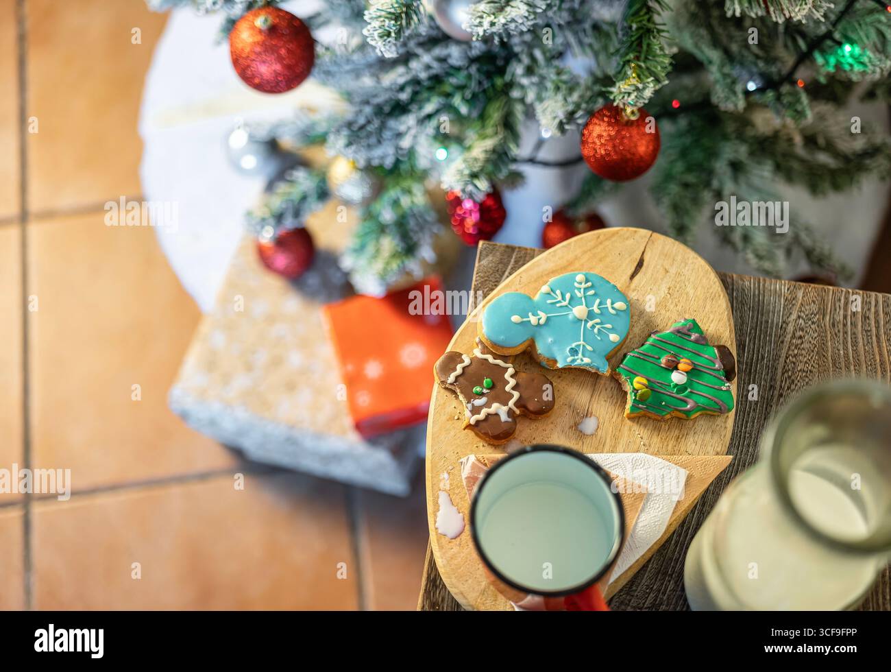 Plan suspendu de biscuits mordus et de lait renversé à côté de cadeaux sous le sapin de Noël. Moment de Noël classique et confortable. Banque D'Images Plan suspendu de biscuits mordus et de lait renversé à côté de cadeaux sous le sapin de Noël. Moment de Noël classique et confortable. Banque D'Images