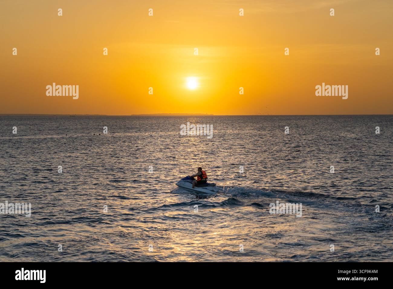 Coucher de soleil doré de Zanzibar avec jet ski et bateau traditionnel silhouette contre l'horizon lumineux. Banque D'Images