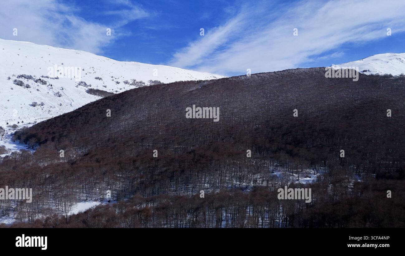 Les collines enneigées créent un paradis hivernal serein, mettant en valeur un paysage paisible et intact où la beauté de la nature prospère sous le bleu vif h. Banque D'Images