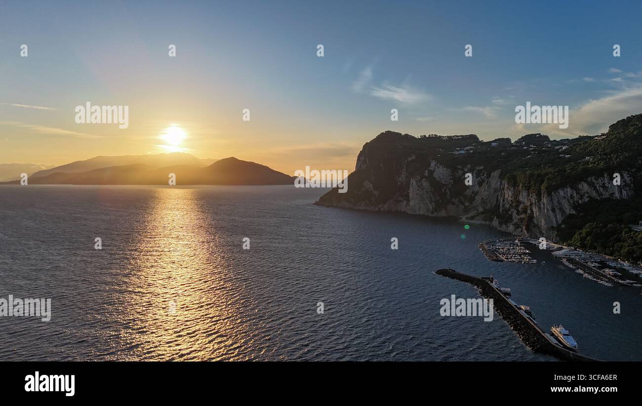 Coucher de soleil doré sur les eaux tranquilles de Capri, peindre l'horizon avec des teintes chaudes et projeter des reflets doux sur la côte sereine Banque D'Images