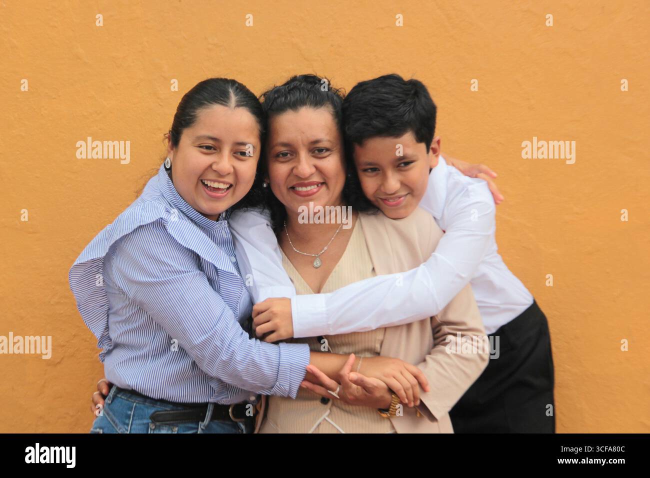 La mère, la fille et le fils latino-américains à la peau foncée montrent leur amour avec des câlins et célèbrent la fête des mères avec leur famille Banque D'Images La mère, la fille et le fils latino-américains à la peau foncée montrent leur amour avec des câlins et célèbrent la fête des mères avec leur famille Banque D'Images
