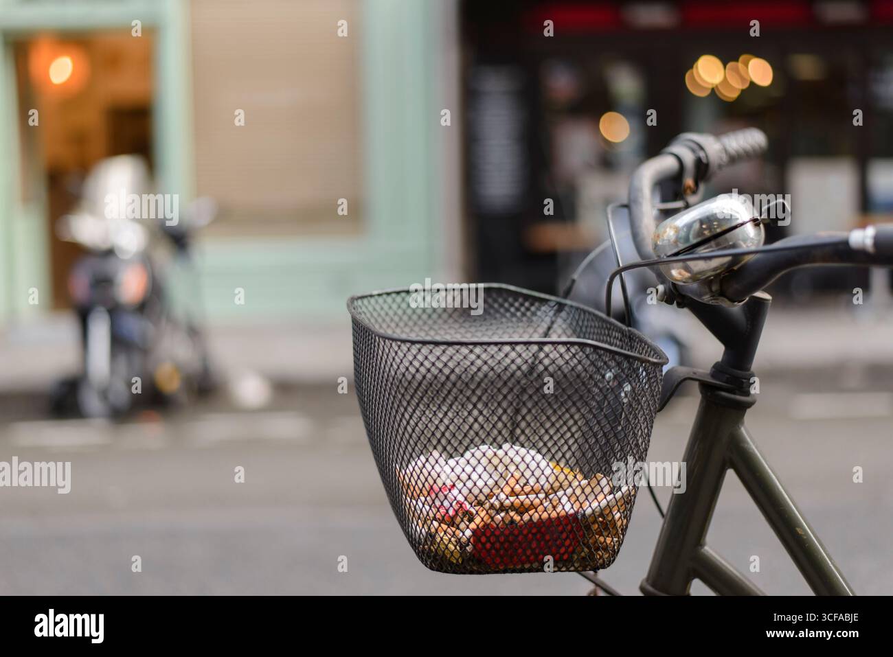 Gros plan d'un vélo avec un panier rempli de mégots de cigarettes et de déchets à Paris Banque D'Images
