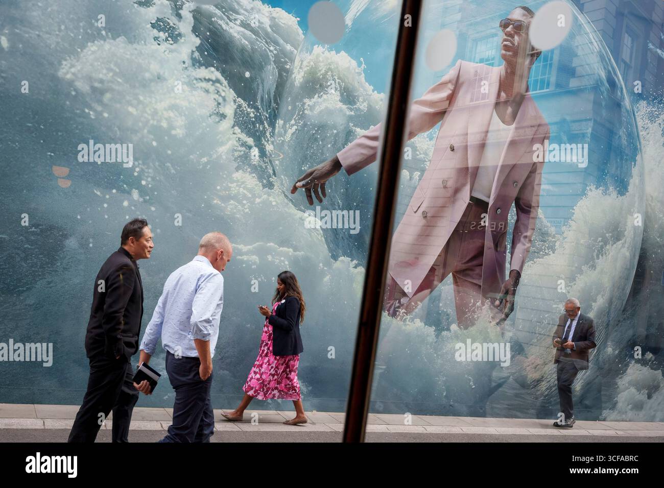 Les membres du public passent sous un grand panneau publicitaire devant la marque Suitsupply à Mayfair, le 21 août 2025, à Londres, en Angleterre. Banque D'Images